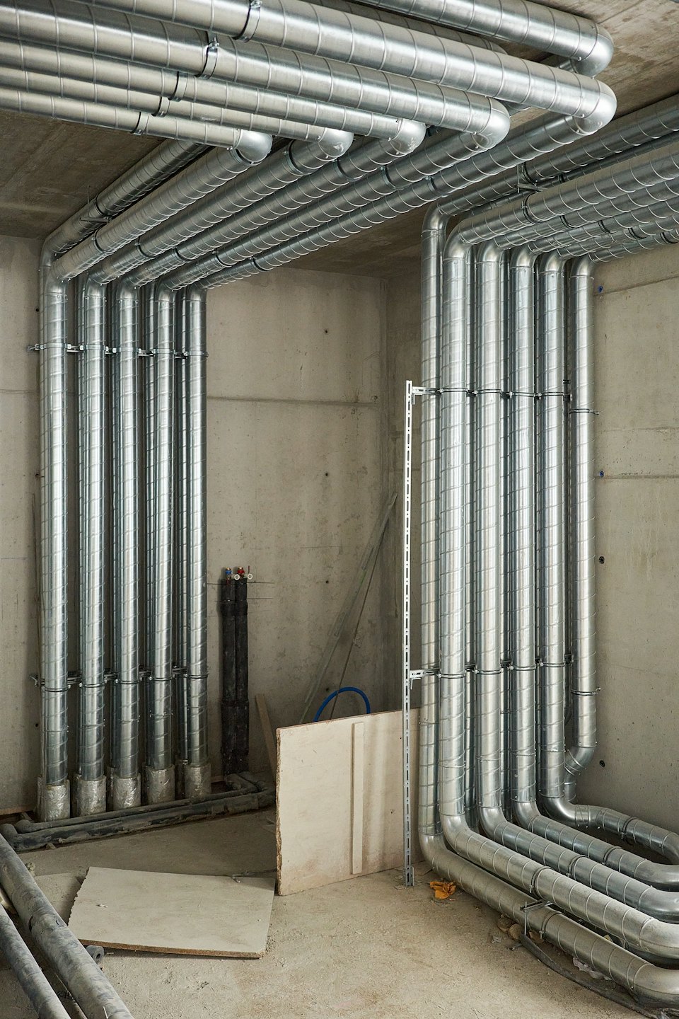 Condotti HVAC in acciaio zincato installati su muri di cemento.