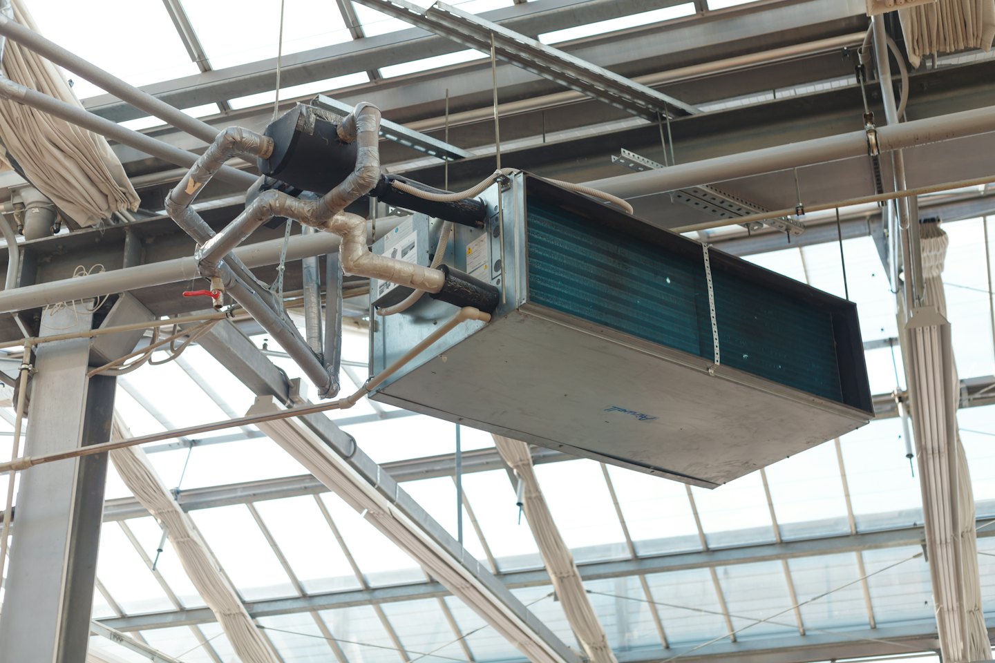 Unità HVAC industriale sospesa sotto un edificio con tetto in vetro.